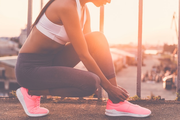 Preparando-se para correr. close de uma mulher jovem e bonita em roupas esportivas, amarrando os cadarços