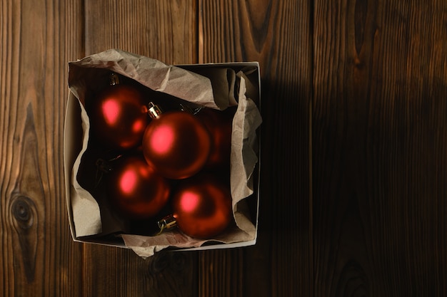Preparando-se para o natal. decorações para a árvore de natal. bolas vermelhas de natal em uma caixa sobre uma mesa de madeira