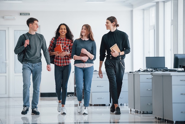 Preparando-se para o trabalho de hoje. Grupo de jovens andando no escritório na hora do intervalo.