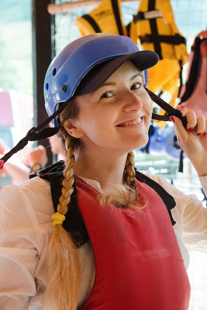 Preparando-se para uma aventura segura na água. mulher sorridente no capacete e colete salva-vidas para rafting.