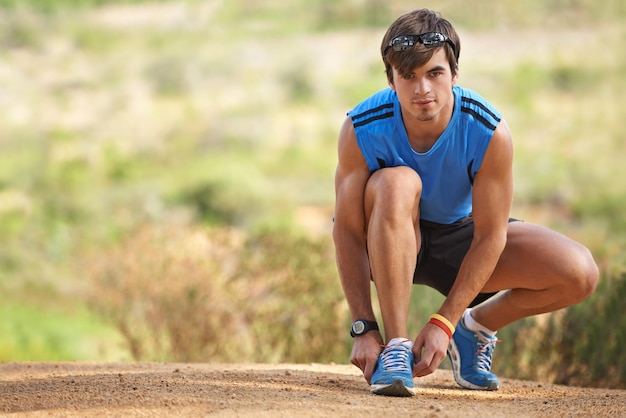 Preparando-se para uma corrida revigorante Um jovem adolescente amarrando os cadarços dos sapatos antes de correr na floresta