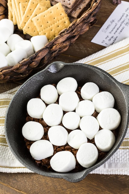 Preparando smores mergulho preparado com grandes marshmallows em panela de ferro fundido.