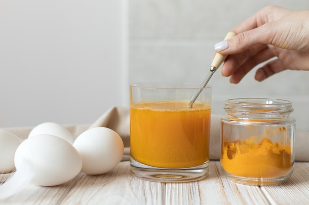 Preparando una solución de cúrcuma seca para teñir huevos de Pascua. Foto de alta calidad