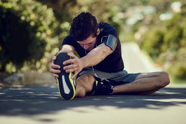 Preparando sus piernas para correr Toma completa de un joven calentando al aire libre antes de un entrenamiento