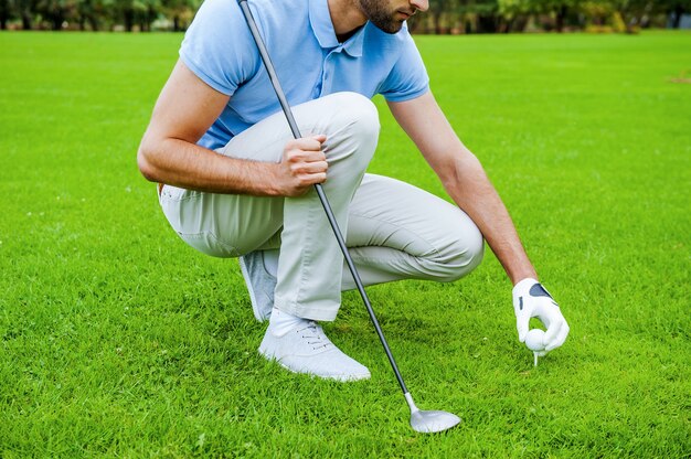 Preparando el tee. Close-up de golfista colocando una pelota de golf en el tee antes