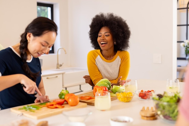 Preparando verduras jóvenes amigos diversos disfrutando de cocinar juntos en una cocina moderna
