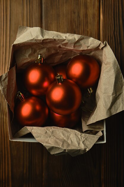 Preparándose para la Navidad. Decoraciones para el árbol de Navidad. Bolas de Navidad rojas en una caja sobre una mesa de madera