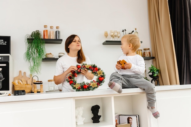 Preparándose para navidad mamá está trabajando en la cocina mientras su hijo se sienta y la mira