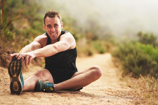 Preparándose para noquear otro entrenamiento Retrato de un joven deportivo que se estira antes de correr afuera