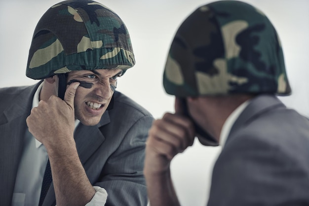 Foto preparándose para la próxima batalla un joven aplicándose pintura de camuflaje en la cara