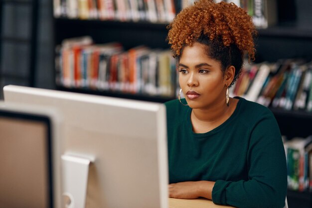 Preparándose para sus exámenes finales Toma de ángulo alto de una joven estudiante universitaria que estudia en la biblioteca