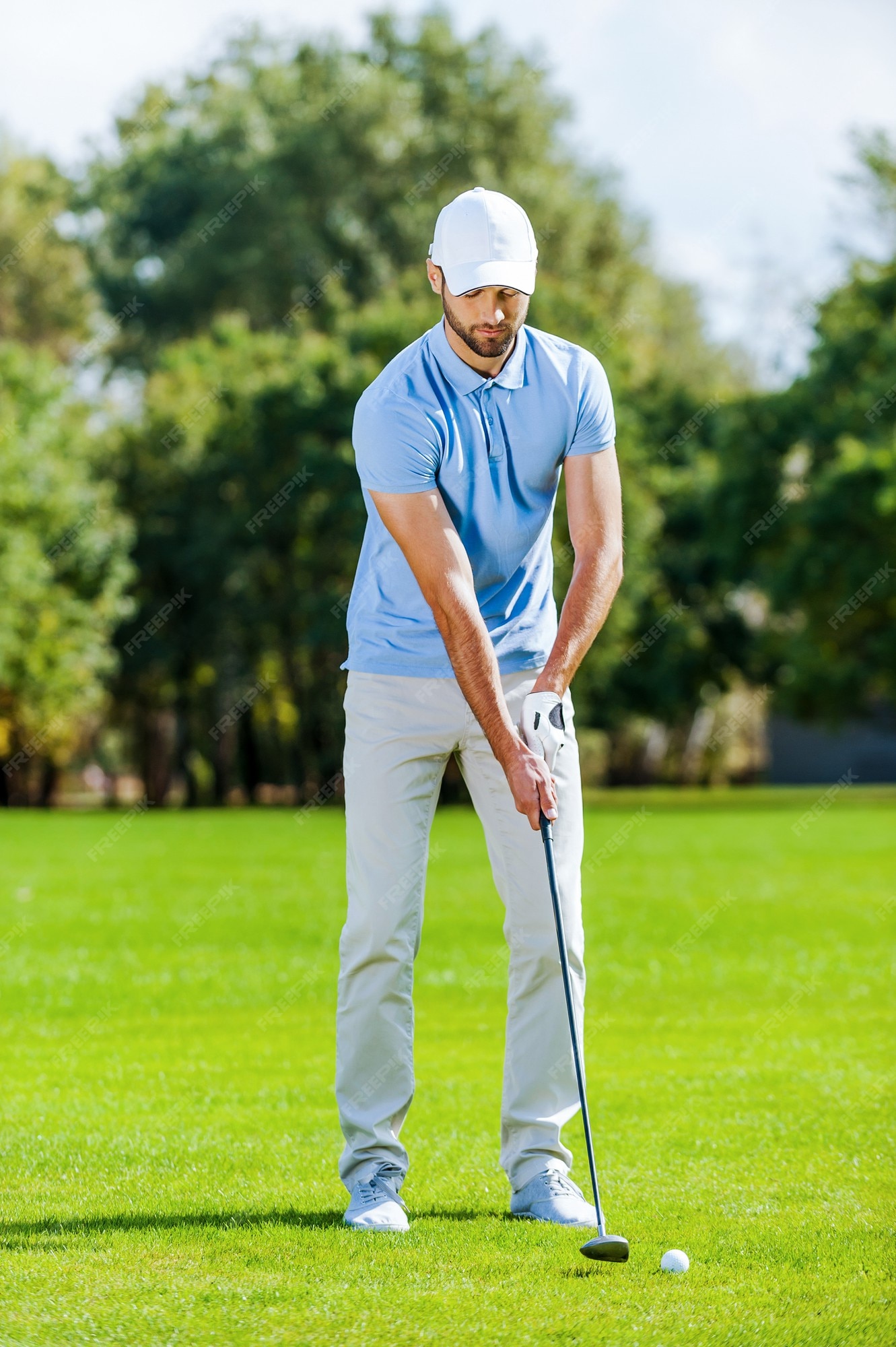 Preparándose para el tiro. longitud total de joven en ropa deportiva jugando al golf mientras de pie en verde | Foto Premium