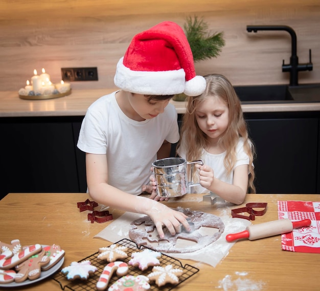 Preparándose para las vacaciones de Navidad. Niños: un niño y una niña están preparando pan de jengibre en la cocina