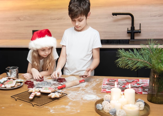 Preparándose para las vacaciones de Navidad. Niños: un niño y una niña están preparando pan de jengibre en la cocina