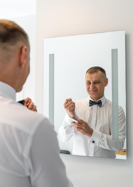 preparar al hombre abrocha los puños de su camisa frente al espejo preparativos de boda