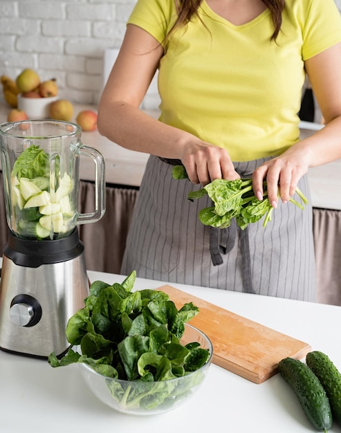 Preparar alimentos saludables Comer y hacer dieta saludable Joven morena haciendo batido verde en la cocina de casa