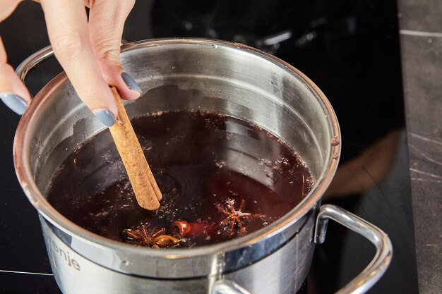 Preparar um delicioso vinho quente com vinho vermelho e especiarias aromáticas em uma cozinha aconchegante