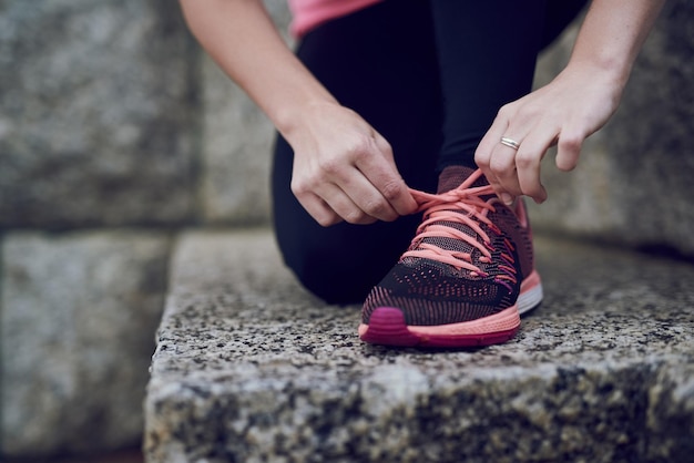 Prepárate para una gran carrera Foto de una mujer joven no identificable atándose los cordones de los zapatos antes de correr en la ciudad