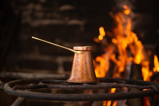 Prepare café en un turco en un fuego abierto. El concepto de un ambiente acogedor y bebidas.