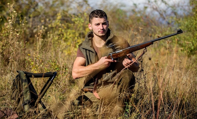 Prepare-se para a caça o que você deve ter ao caçar o ambiente natural recarregue o conceito do rifle equipamento de caça e medidas de segurança homem com fundo da natureza do equipamento de caça do rifle