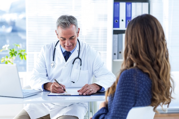 Prescripción masculina de la escritura del doctor para la mujer en hospital