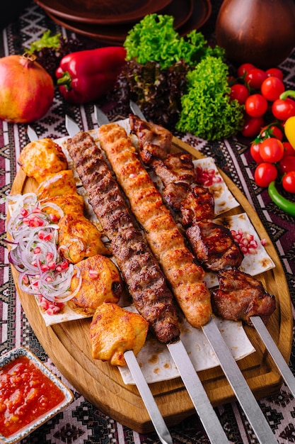 Presentación apetitosa de una variedad de pinzas de barbacoa a la parrilla en una tabla de madera con verduras frescas