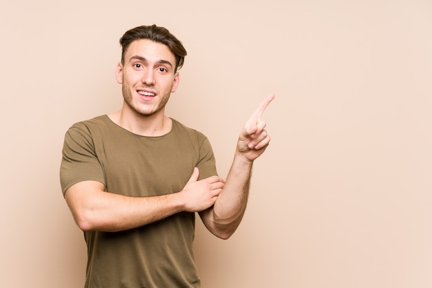 Presentación caucásica joven del hombre aislada que sonríe alegremente que señala con el índice lejos.