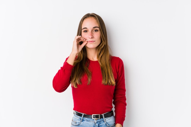 Foto presentación caucásica joven de la mujer aislada con los dedos en los labios que guardan un secreto.