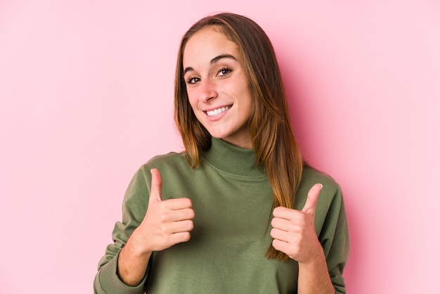 Presentación caucásica joven de la mujer aislada levantando ambos pulgares para arriba, sonriendo y confiados.