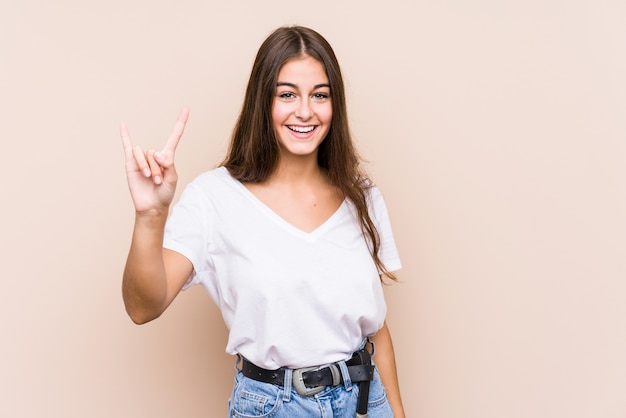 Presentación caucásica joven de la mujer aislada mostrando un gesto de los cuernos como concepto de la revolución.