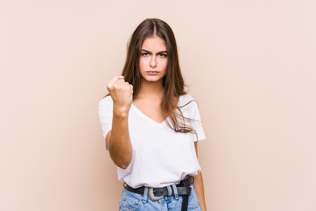 Foto presentación caucásica joven de la mujer aislada que muestra el puño a la cámara, expresión facial agresiva.