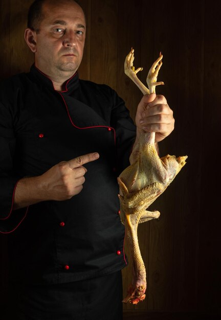 Presentación de pollo joven crudo antes de cocinar El chef señala con el dedo el pollo para la selección Concepto de menú para hotel o restaurante