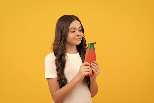 Presentación de producto cosmético para niño adolescente con gel de ducha niña feliz sostener botella de champú