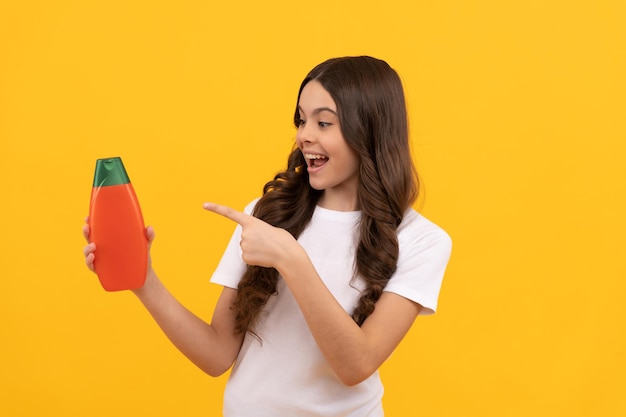 Presentación de producto cosmético para niño adolescente con gel de ducha niña feliz sostener botella de champú