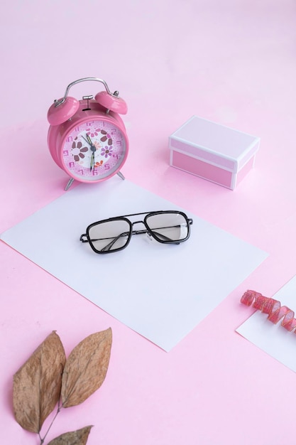 Presentación del producto del reloj de caja de regalo de gafas cuadradas de Idea de concepto minimalista y hojas secas sobre fondo de papel rosa