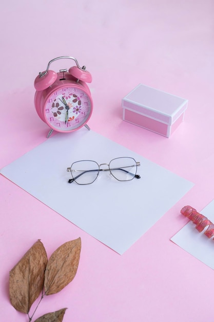 Presentación del producto del reloj de caja de regalo de gafas cuadradas de Idea de concepto minimalista y hojas secas sobre fondo de papel rosa