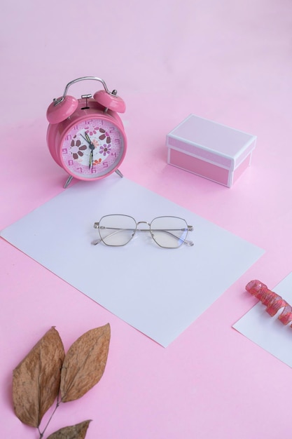 Presentación del producto del reloj de caja de regalo de gafas cuadradas de Idea de concepto minimalista y hojas secas sobre fondo de papel rosa