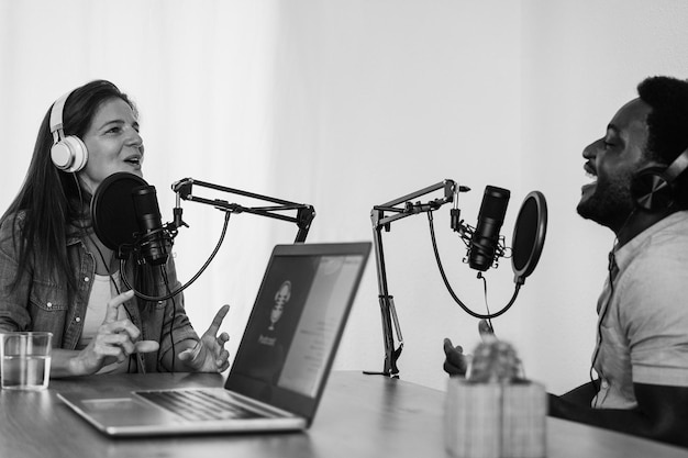 Presentadores multirraciales que transmiten podcast en un estudio digital Enfoque suave en el rostro femenino Edición en blanco y negro