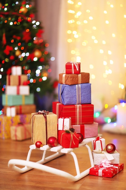 Presentar cajas en trineo sobre piso de madera cerca del árbol de Navidad, en el interior