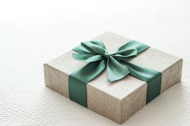 Presente de férias e entrega de compras on-line de luxo embrulhada caixa de presente de linho com fita verde na cama no quarto estilo campestre chique