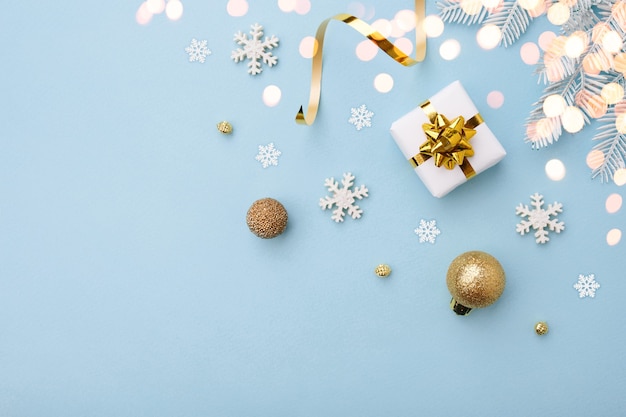 Presente de Natal branco com laço de ouro e enfeites em fundo azul, vista superior. Cartão de feliz Natal e boas festas.