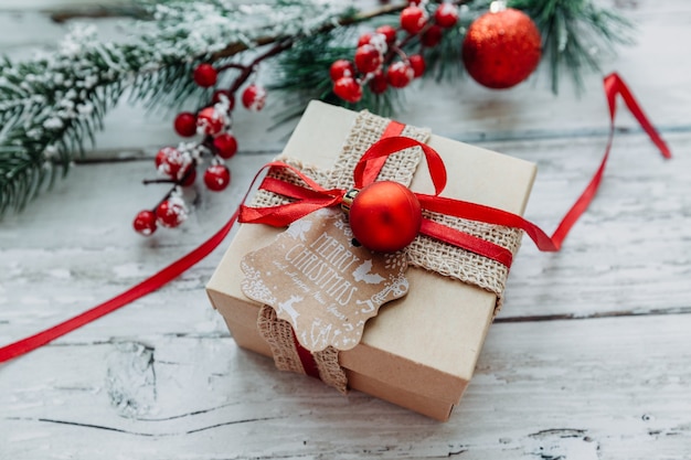 Presente de Natal com uma fita vermelha em um fundo de madeira com flocos de neve