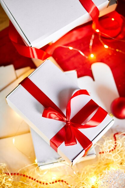 Presente de Natal DIY embrulhando caixa branca de presente de Natal com uma fita vermelha, decoração festiva em cima da mesa.
