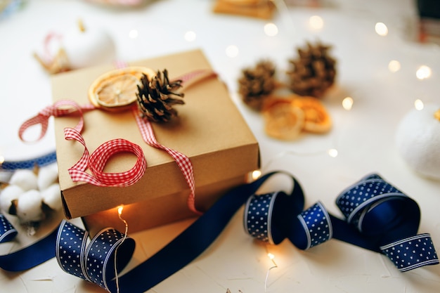 Presente de Natal e decorações na mesa texturizada branca festiva ainda vida caixa de papelão costela colorida ...