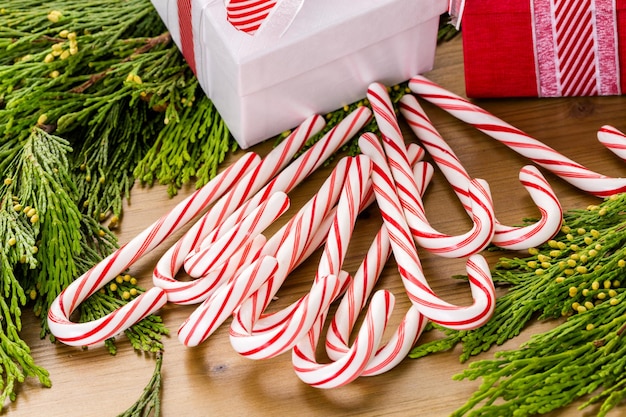 Presente de Natal em uma caixa branca na mesa de madeira com galhos verdes vivos.