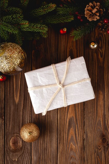 Presente de Natal embrulhado ecológico minimalista na mesa de madeira com galhos de árvore do abeto e bolas de Natal.