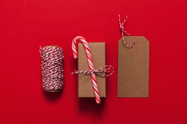 Presente de natal festivo com bastão de doces em um fundo vermelho