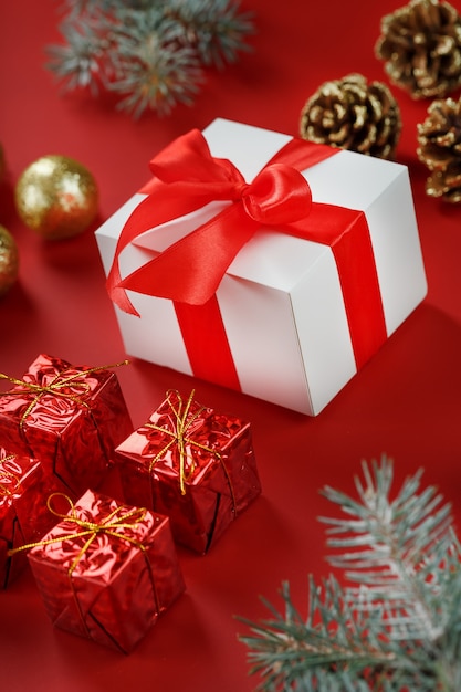 Presente de Natal na forma de uma caixa branca com um laço vermelho em volta das decorações de Natal