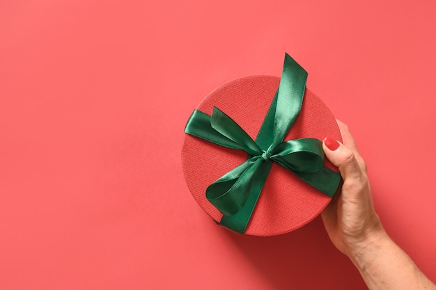 Presente de Natal na mão da mulher sobre fundo vermelho