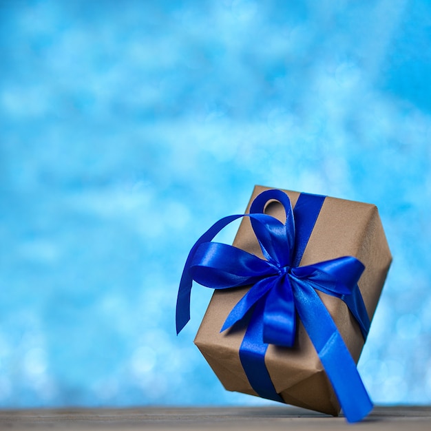 Foto presente de natal ou ano novo com uma fita azul em uma mesa de madeira rústica em um bokeh à noite azul